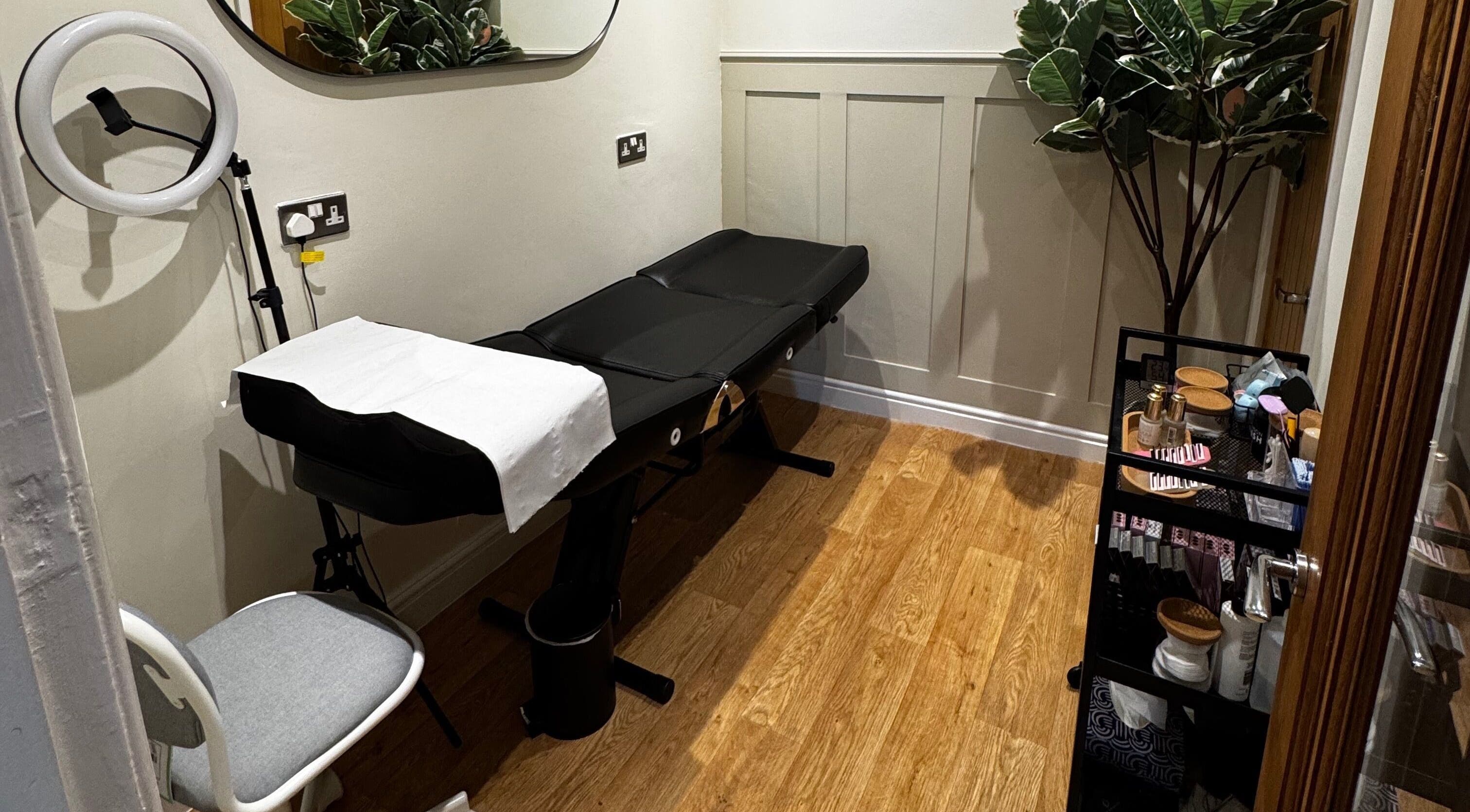 AJ Lash & Brow's serene treatment room in Bristol, England, GB featuring a sleek black beauty bed.