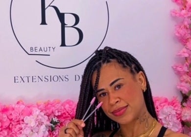 Styliste cheveux à Ka Beauty Studio, Clermont-ferrand, entourée de fleurs roses vibrantes.