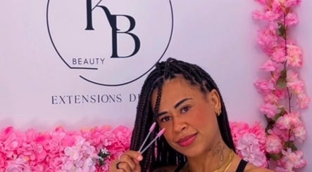 Styliste cheveux à Ka Beauty Studio, Clermont-ferrand, entourée de fleurs roses vibrantes.