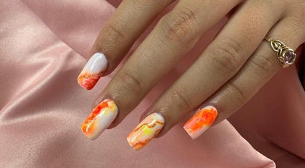 Nail art lumineuse à 'Una'Una, Saint-avé, Bretagne, FR. Design marbré orange vibrant sur fond satin rose.