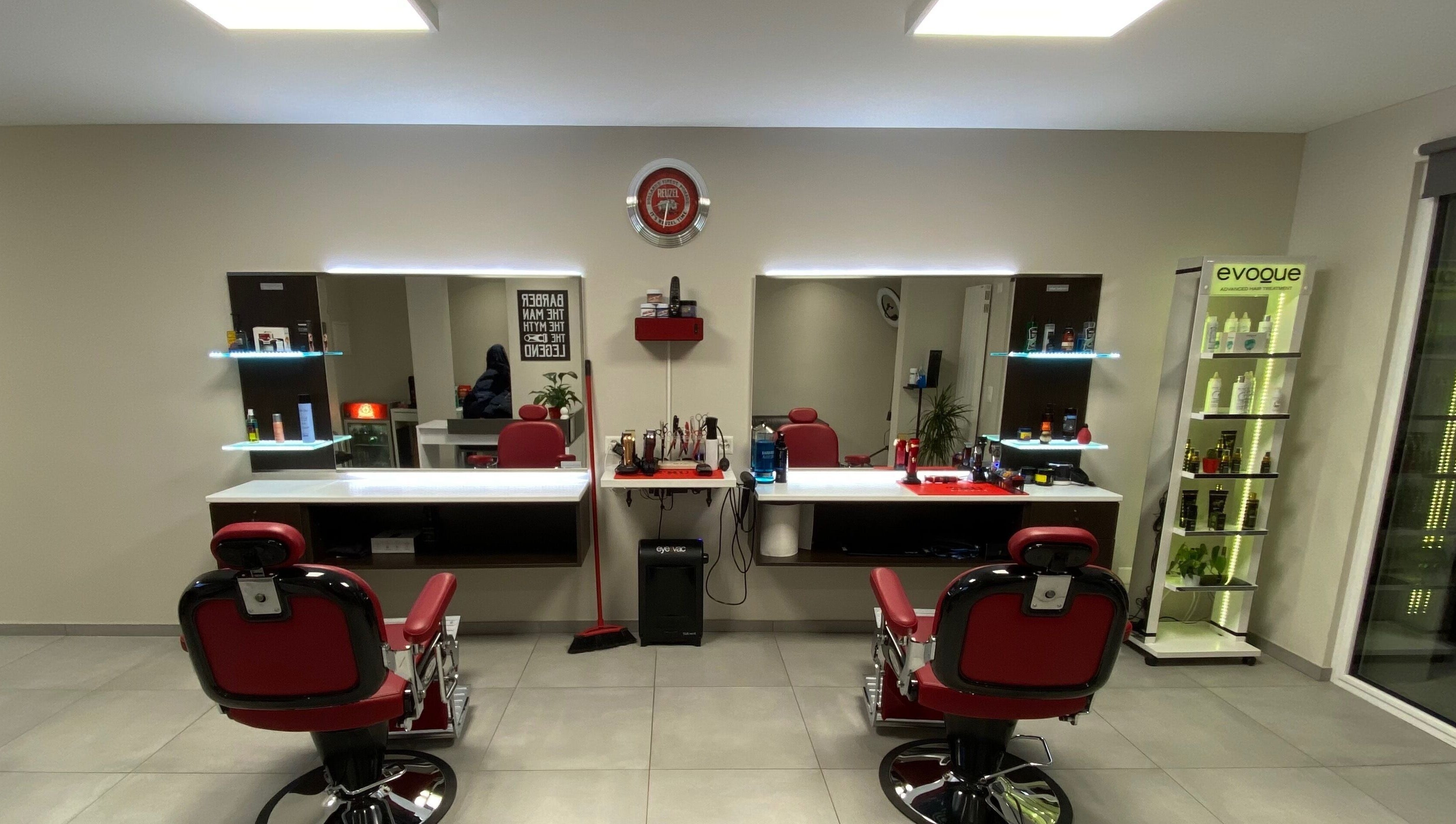 Interni eleganti di Il Barbiere di Cureglia, a Cureglia, Ticino, CH, con poltrone rosse e specchi moderni.