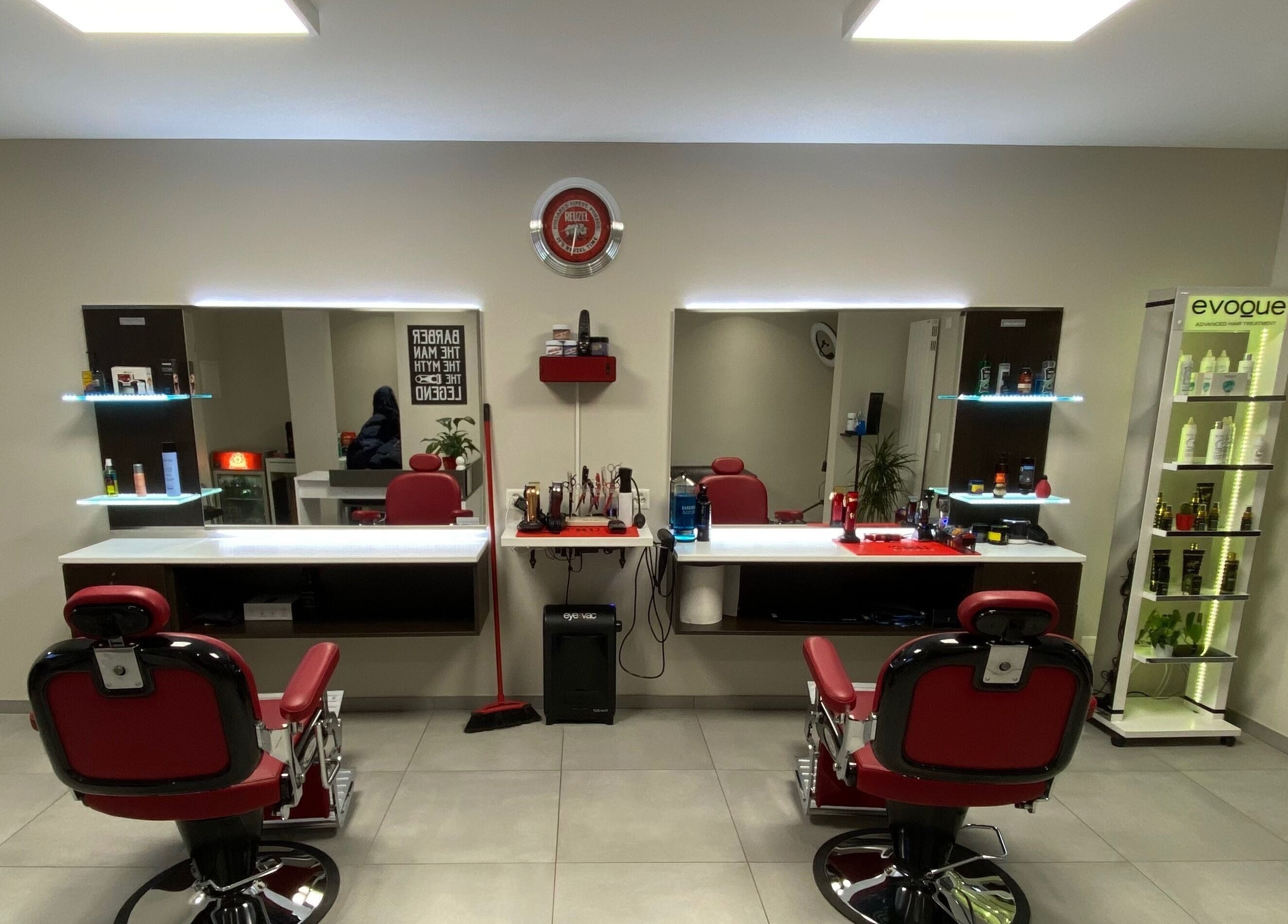 Interni eleganti di Il Barbiere di Cureglia, a Cureglia, Ticino, CH, con poltrone rosse e specchi moderni.