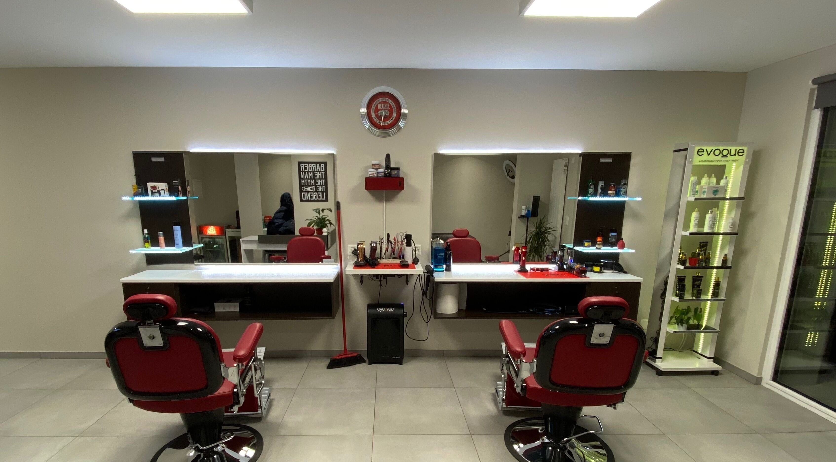 Interni eleganti di Il Barbiere di Cureglia, a Cureglia, Ticino, CH, con poltrone rosse e specchi moderni.