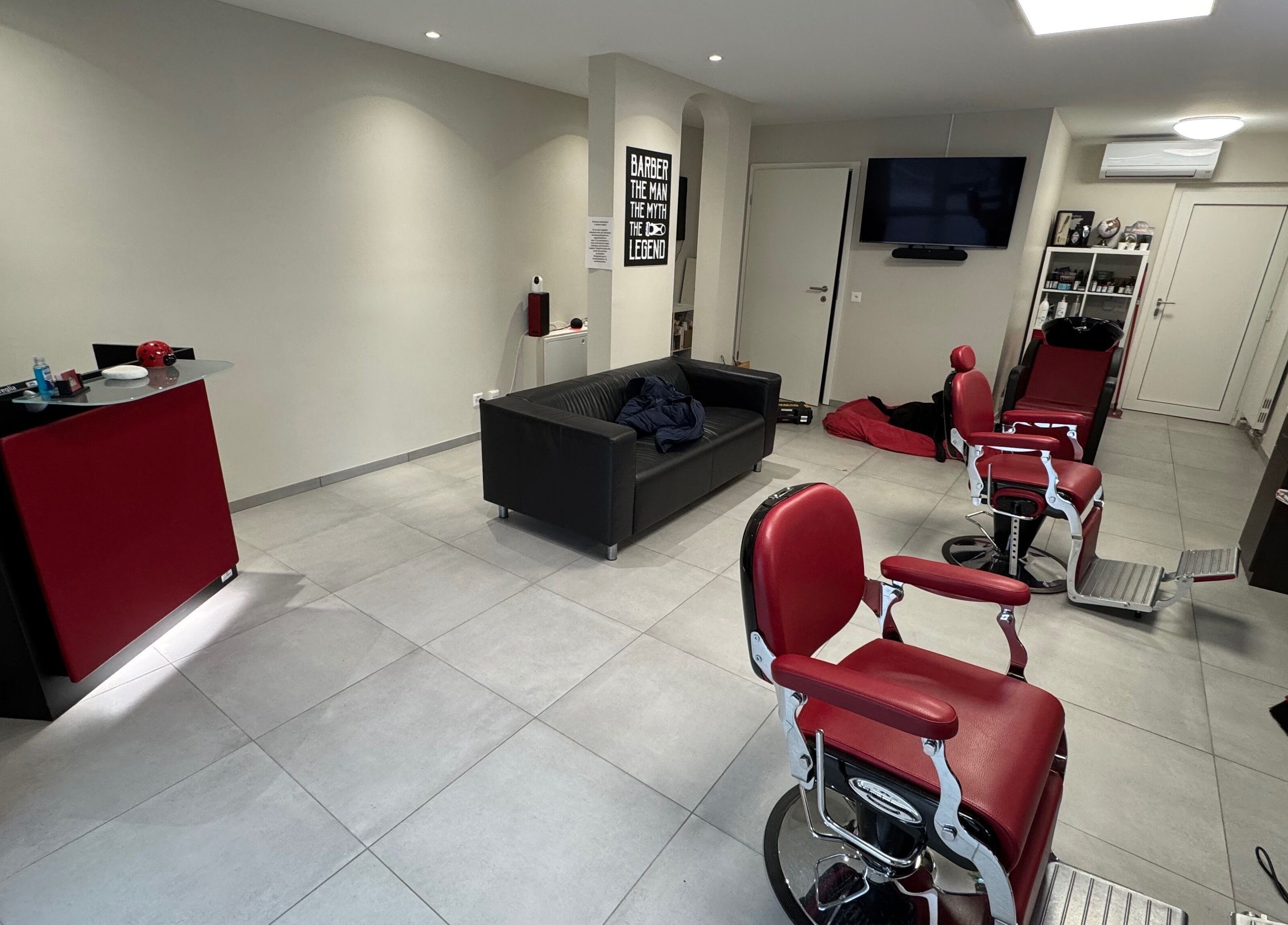 Interno di Il Barbiere di Cureglia, elegante salone a Cureglia, Ticino, CH, con poltrone rosse.