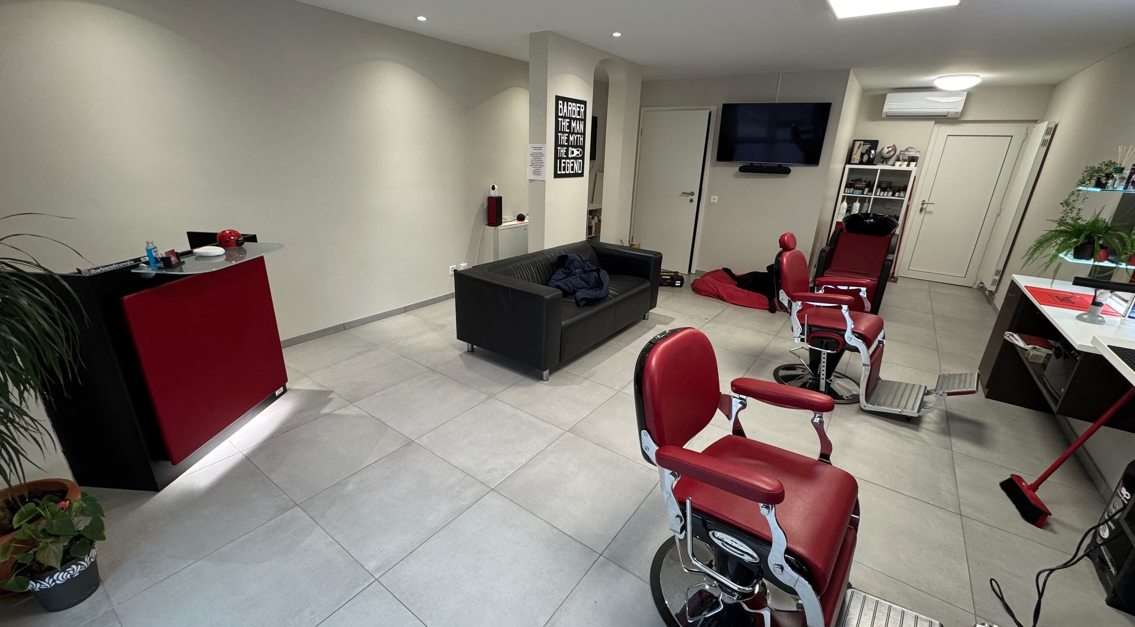 Interno di Il Barbiere di Cureglia, elegante salone a Cureglia, Ticino, CH, con poltrone rosse.