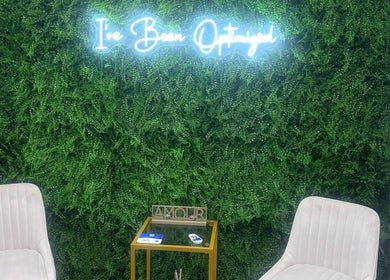 Sculpt With Sherree in Luton, England, GB features plush chairs against a lush green wall with neon signage.