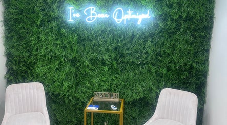 Sculpt With Sherree in Luton, England, GB features plush chairs against a lush green wall with neon signage.