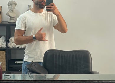Homem em salão de barbearia no Terminal 4, Guimarães, Guimarães, PT, refletido no espelho com cadeira à frente.