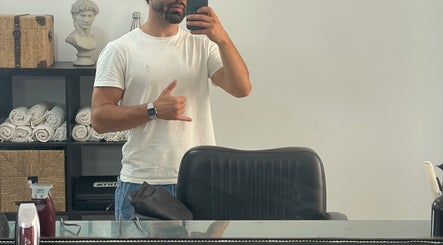 Homem em salão de barbearia no Terminal 4, Guimarães, Guimarães, PT, refletido no espelho com cadeira à frente.