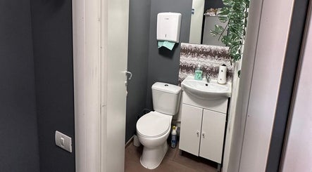 Baia modernă a salonului Frizerie din București, București, RO, cu accente elegante și mobilier alb.