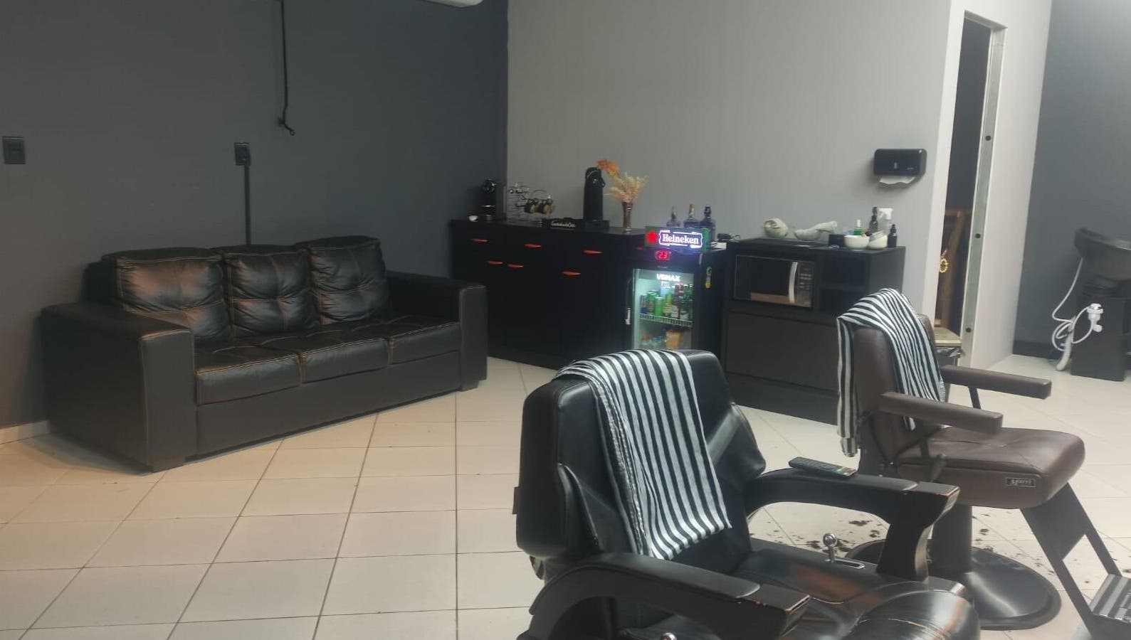 Interior moderno da Barbearia Dom Pascoal, Santa Catarina, BR, com cadeiras de couro elegantes e móveis confortáveis.