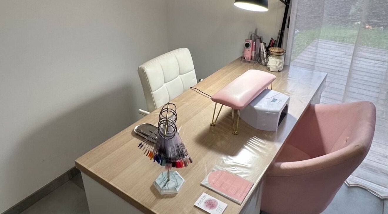 Espace manucure élégant chez La Pose Malleen, à Rivière-sur-tarn, Occitanie, FR, avec chaise rose et table en bois.