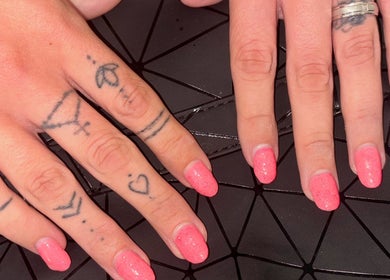 Close-up of pink manicured hands with tattoos at NJK Beauty, Shirebrook, England, GB.
