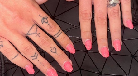 Close-up of pink manicured hands with tattoos at NJK Beauty, Shirebrook, England, GB.