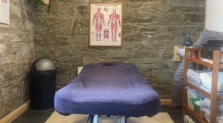 Cozy massage room at Marie’s Sports and Wellbeing Massage, Porthleven, England, GB with anatomical poster.