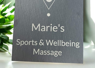 Signage of Marie’s Sports and Wellbeing Massage in Porthleven, England, GB with lush green plants.