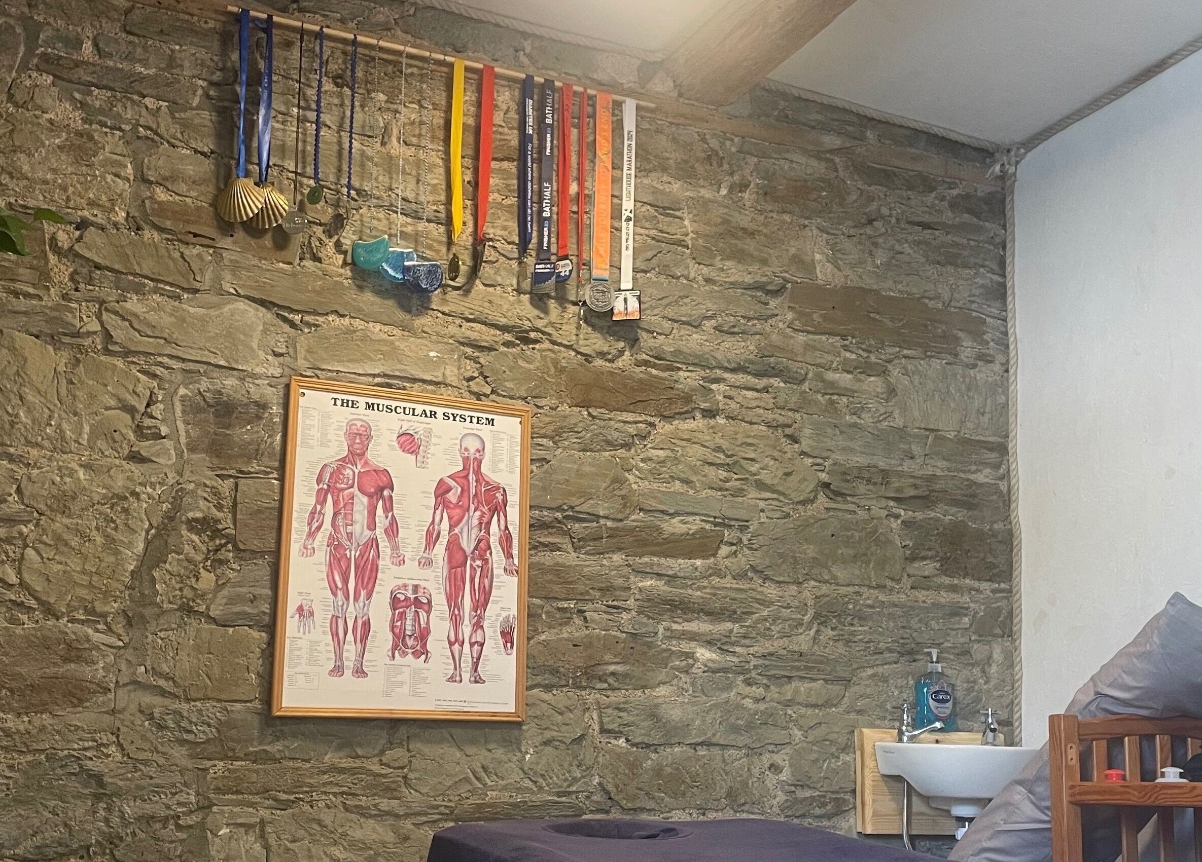 Cozy massage room at Marie’s Sports and Wellbeing Massage, Porthleven, England, GB, with stone walls and decor.