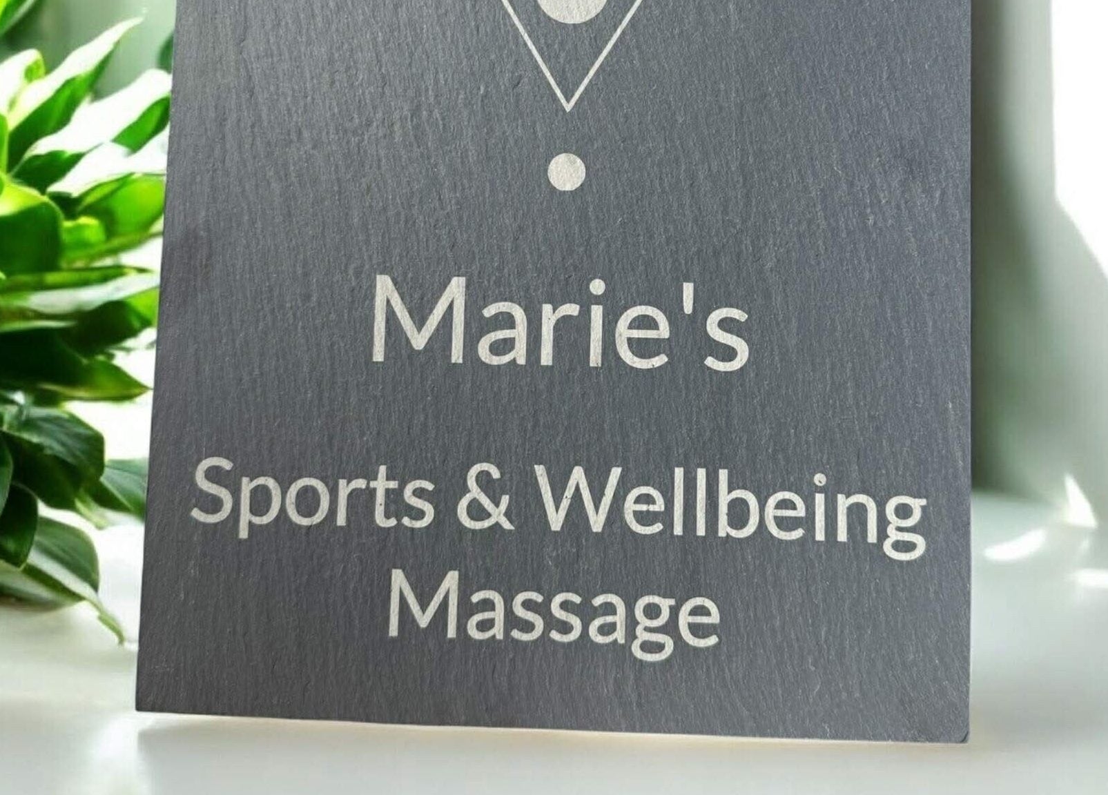Elegant sign for Marie's Sports and Wellbeing Massage, Porthleven, England, GB, surrounded by lush greenery.