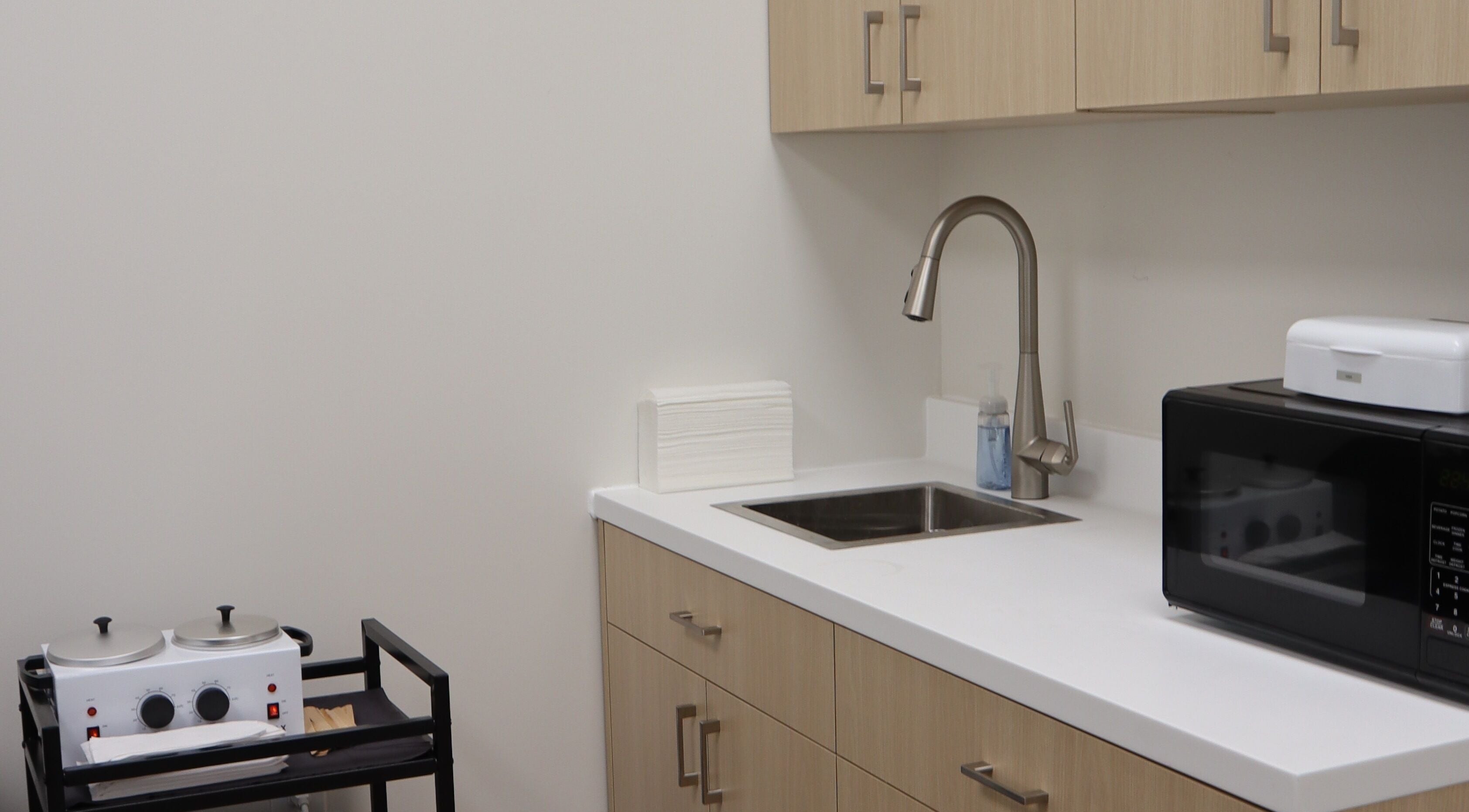 Modern skincare setup at DIVINE DERMABAR, Toronto, Ontario, CA featuring sleek cabinetry and a dual wax heater.