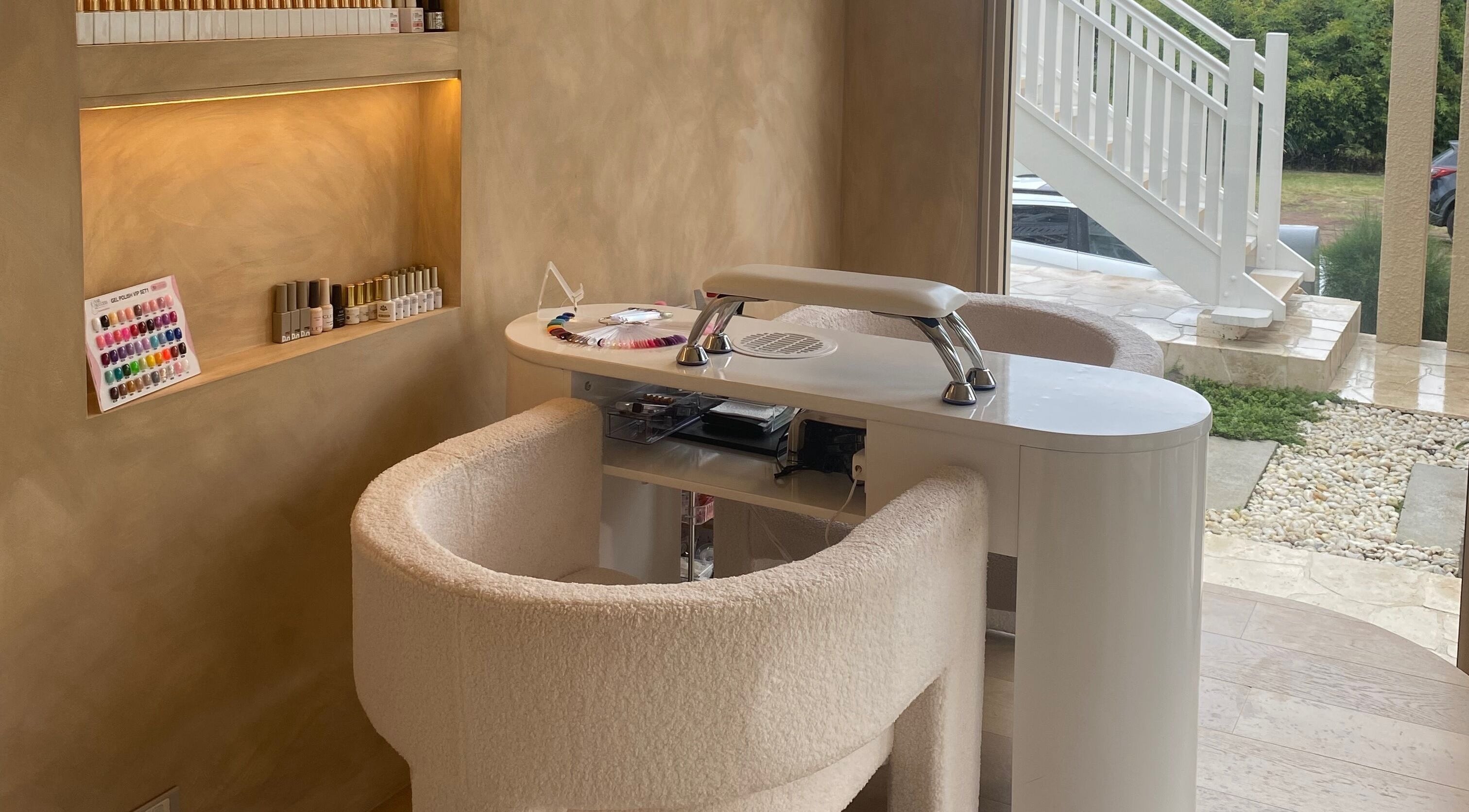 Elegant nail salon station at Sugaplum Studio in Albion, Queensland, AU, featuring plush chairs and nail polish display.