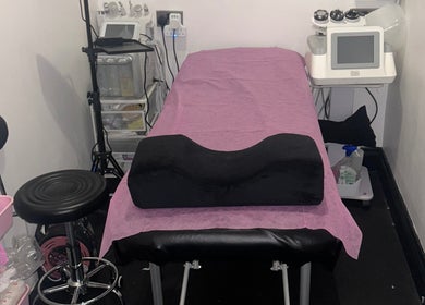 Cozy treatment room at Hans Beauty Haven in London, England, GB, featuring a pink-covered massage table with equipment.