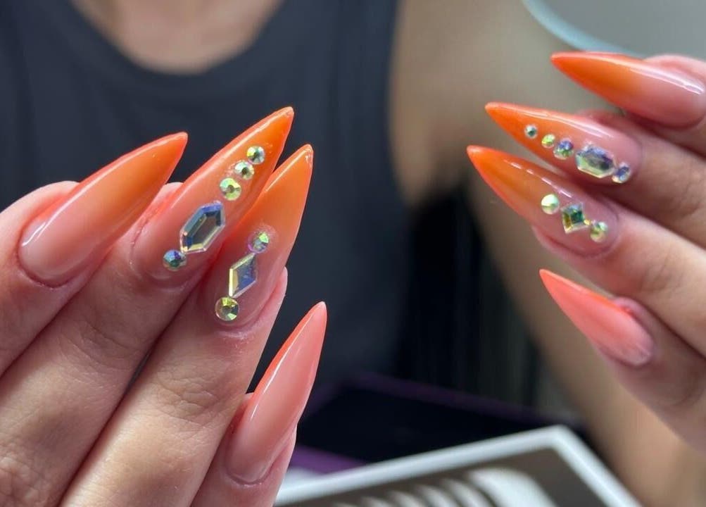 Elegant gem-studded nails at Zamira Nails, Birmingham, England, GB showcasing vibrant orange artistry.