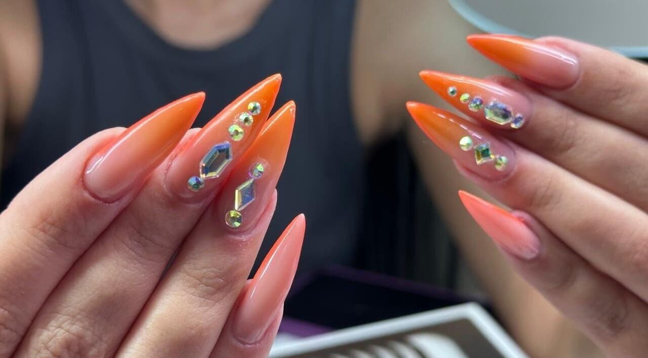 Elegant gem-studded nails at Zamira Nails, Birmingham, England, GB showcasing vibrant orange artistry.