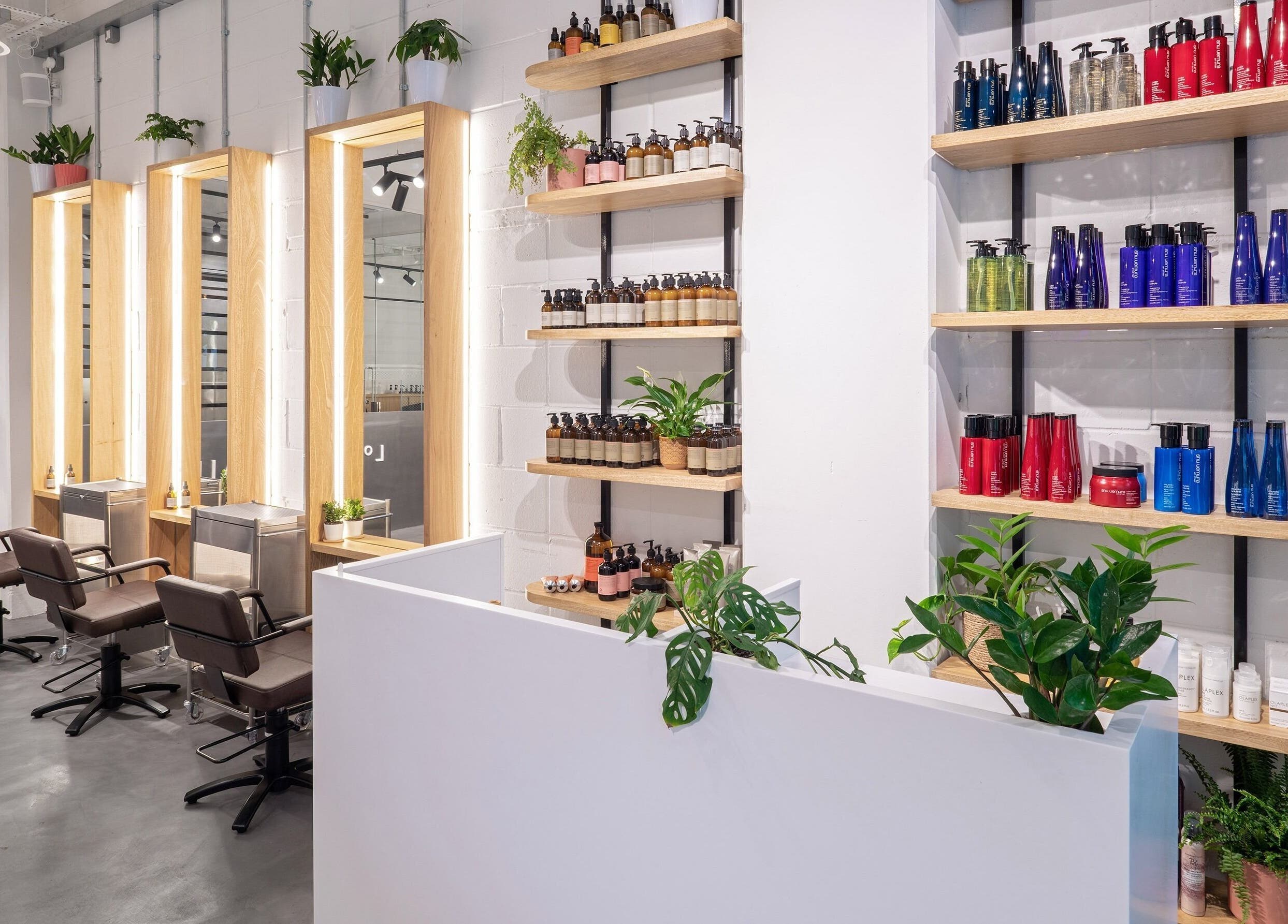 Stylish interior of Vixen & Blush Hair Extensions, London, England, GB, showcasing salon chairs, plants, and products.