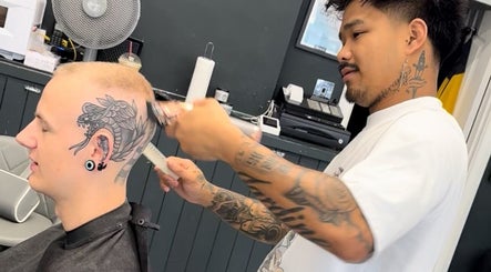 Talent at S.B.T Impact Barbers in Old Sarum, England, GB, tattooed stylist expertly trims client's hair.