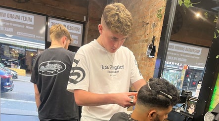 Stylist at S.B.T Impact Barbers, Old Sarum, England, GB, skillfully trims a client's hair in a modern salon setting.