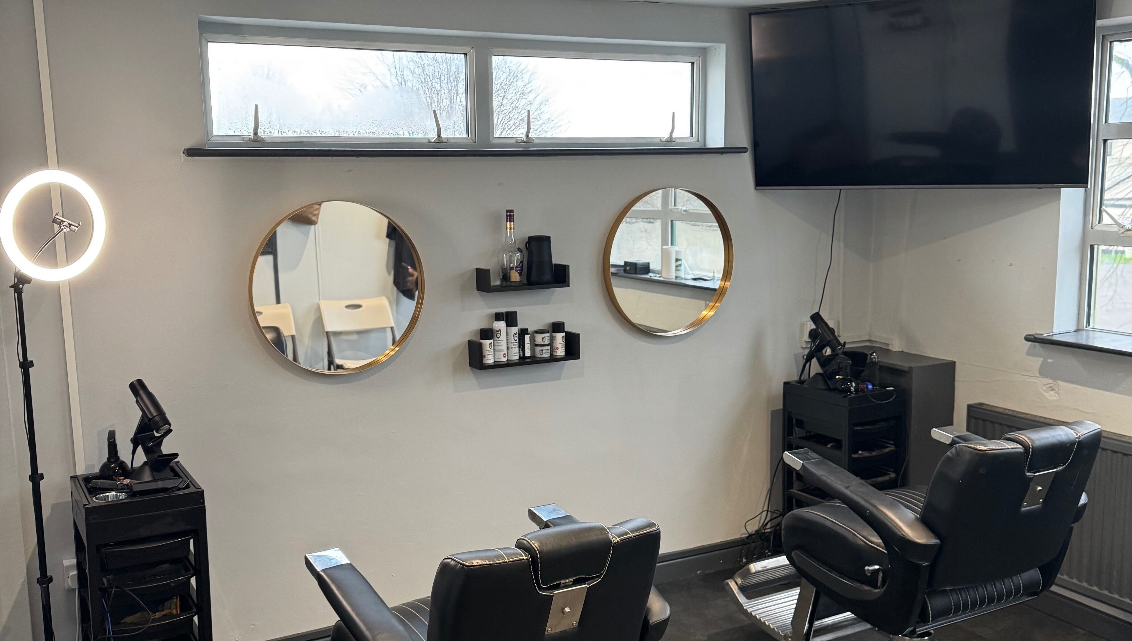 Modern barber chairs at S.B.T Impact Barbers in Old Sarum, England, GB with stylish mirrors and equipment.