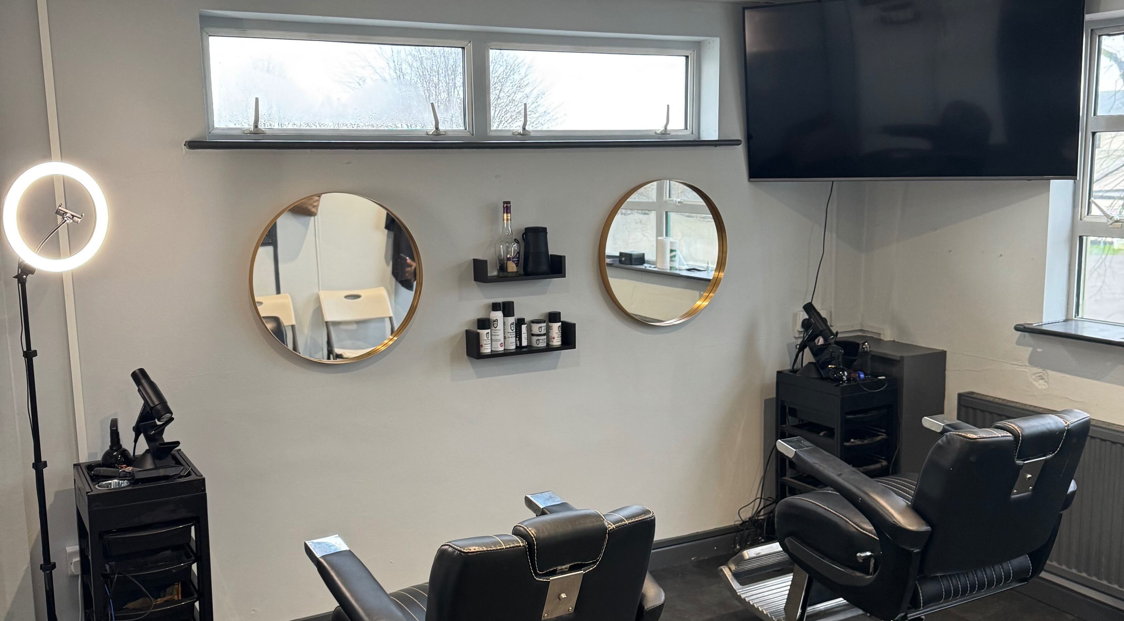 Modern barber chairs at S.B.T Impact Barbers in Old Sarum, England, GB with stylish mirrors and equipment.