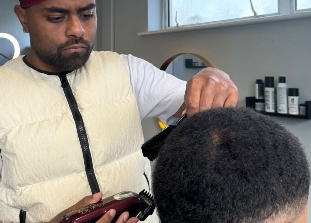 Barber at S.B.T Impact Barbers in Old Sarum, England, expertly trimming a client's hair.