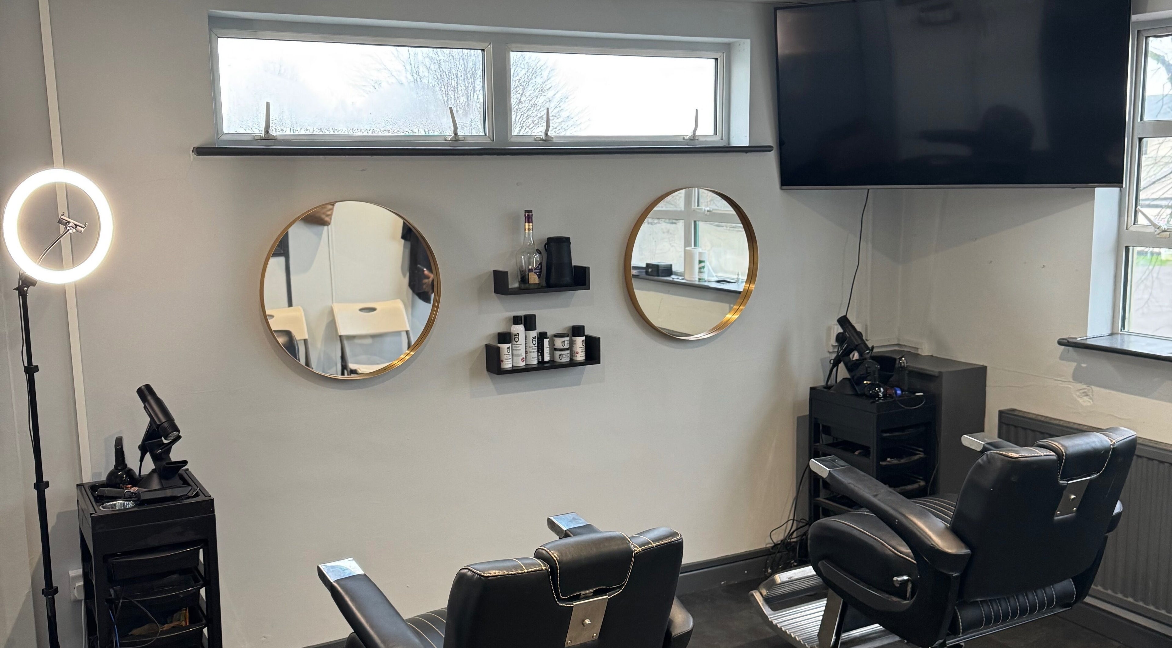 Sophisticated interior at S.B.T Impact Barbers in Old Sarum, England, GB, featuring modern chairs and mirrors.