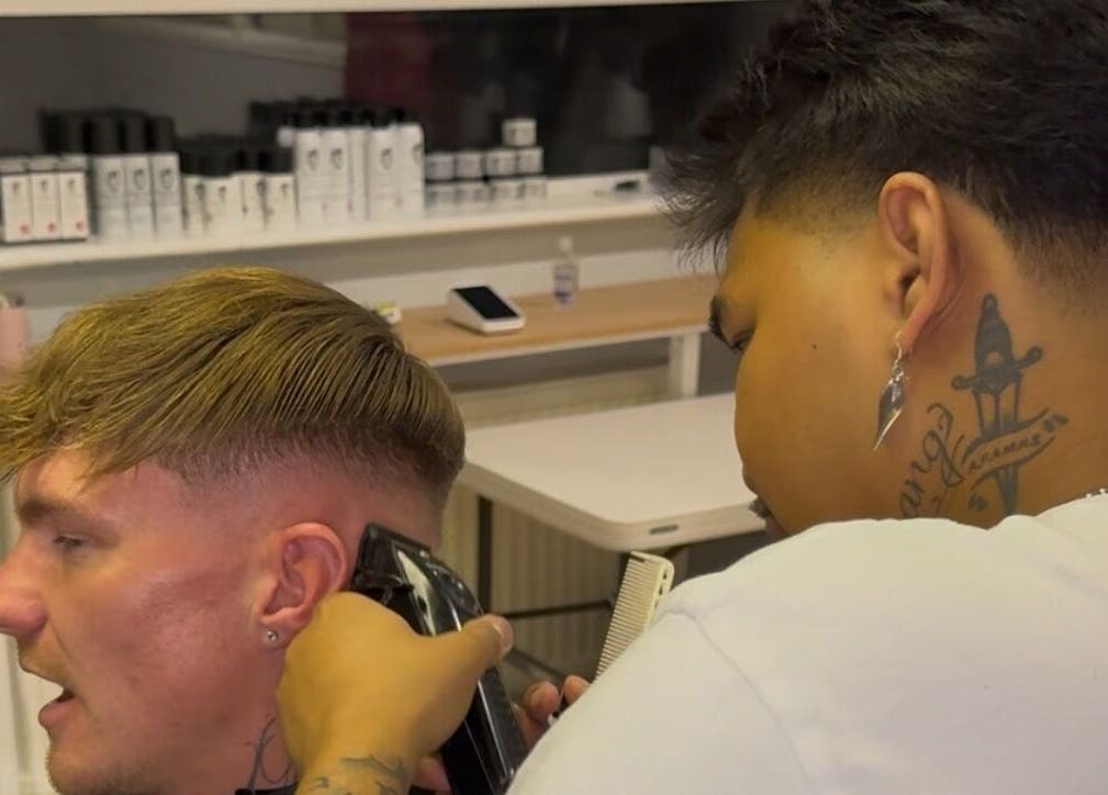 Barber at S.B.T Impact Barbers in Old Sarum, England, GB giving a haircut with expertise and focus.