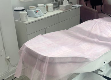 Sala de tratamento no Marisa Craveiro Sugaring em Coimbra, PT com uma marquesa coberta com tecido rosa.
