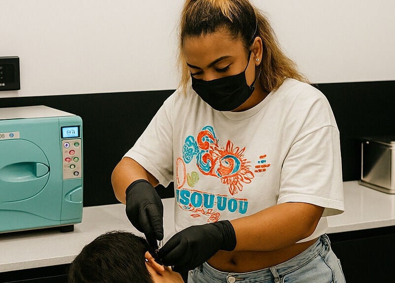 Artisan expert à Sousou Piercing Lab à Saint-denis réalisant un perçage d'oreille avec soin et précision.