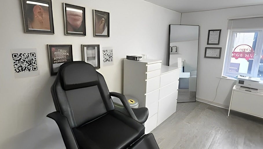 Piercing studio at Anya Celyn Piercings, Amlwch, Wales, GB, featuring a black chair and framed artwork.