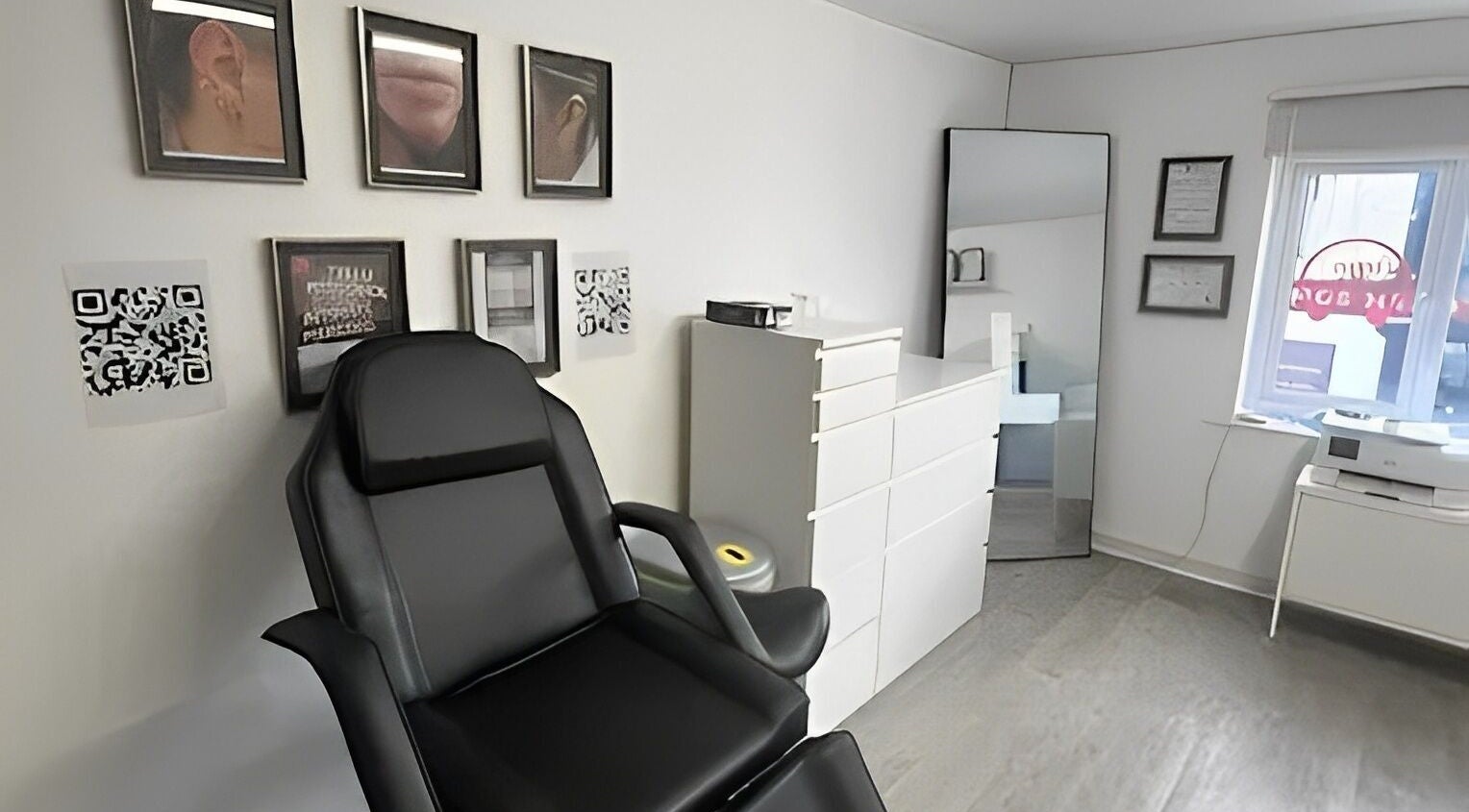 Piercing studio at Anya Celyn Piercings, Amlwch, Wales, GB, featuring a black chair and framed artwork.