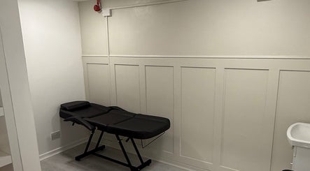 Minimalist piercing room at Anya Celyn Piercings, Amlwch, Wales, GB, with a sleek black chair.