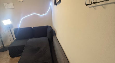 Sala de espera acogedora en Kyiscejas, Barcelona, Catalunya, ES con sofá negro y luz suave.