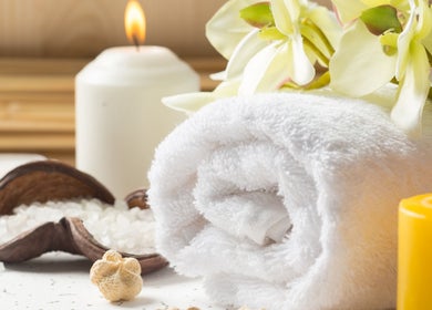 Bougie allumée et serviette blanche à CréoliaSens, Baie-mahault, Basse-terre, GP, illustrant une ambiance de spa.