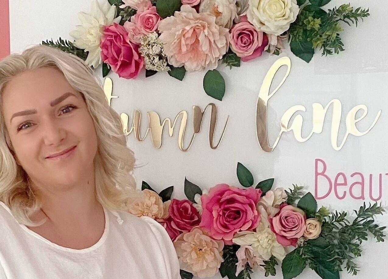 Smiling woman at Autumn Lane Beauty, Margate, Kwazulu-natal, ZA with floral decor in the background.