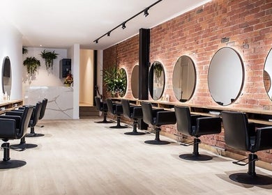 Modern salon interior at Glamzy in Western Province, LK with elegant styling stations and chic chairs.