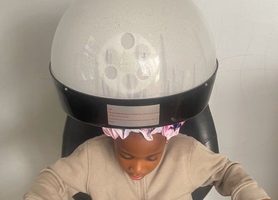 Young client enjoying a steam treatment at Cultured Curls, London, England, GB under a sleek hair steamer.
