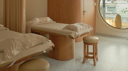 Phòng spa tại Imakoko, Hồ Chí Minh với giường đôi, thiết kế gỗ sang trọng, cửa sổ tròn thoáng đãng.