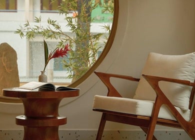 Không gian thiền tại Imakoko, Hồ Chí Minh, VN, với ghế gỗ và bàn trước cửa sổ tròn.