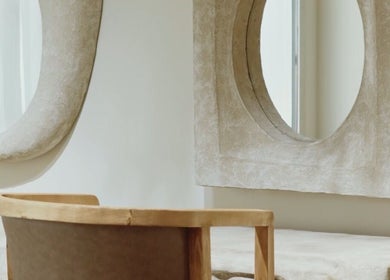 Chic minimalist interior at Mahshid hair club, Muscat, featuring unique mirrors and wooden seating.