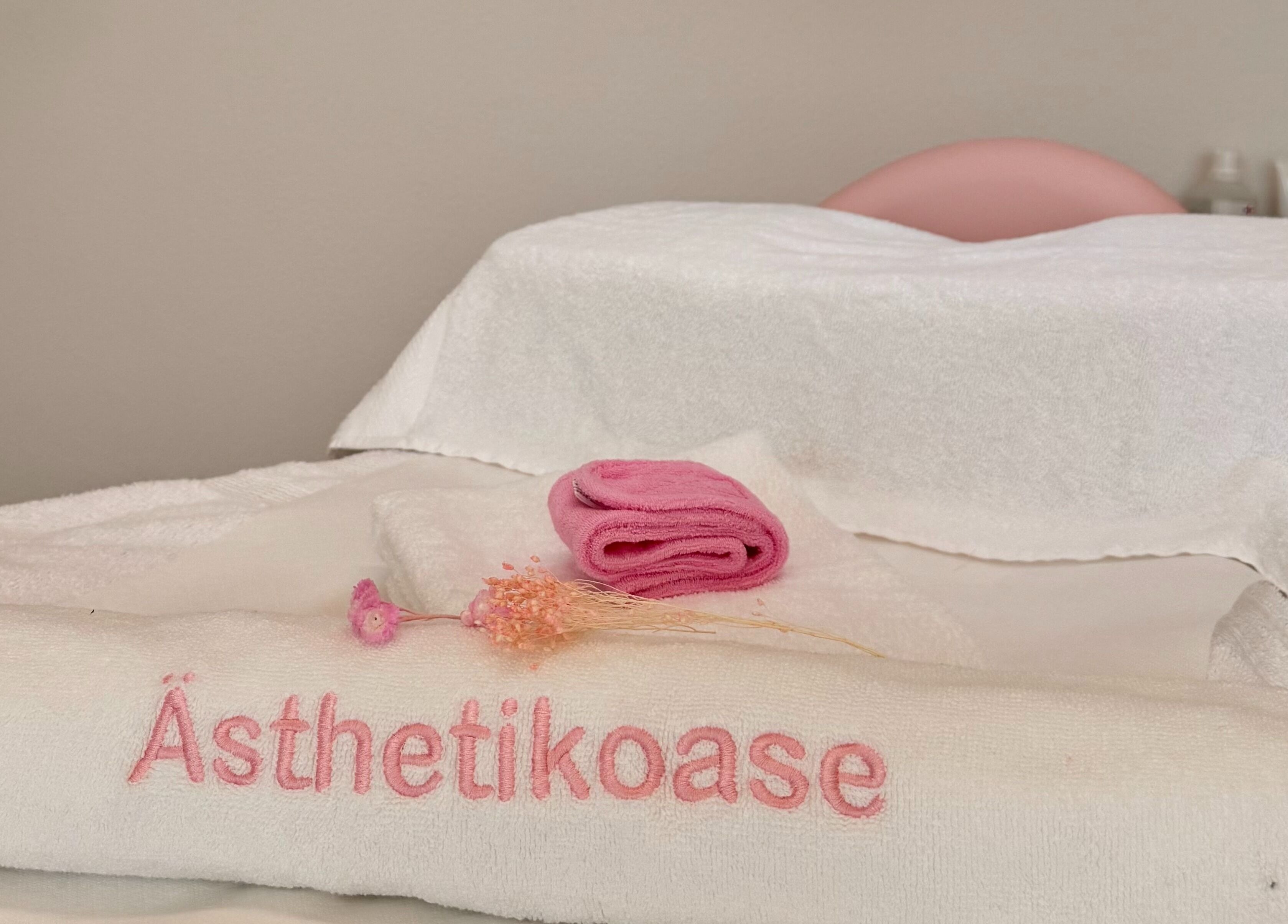 Massageliege bei Ästhetikoase Landa in Ebikon, Luzern, CH mit weichen Handtüchern und rosafarbenem Akzent.