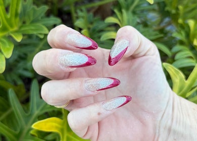 Elegant red and silver glitter nails at Beauty Point GC, Robina, Queensland, AU amidst lush greenery.
